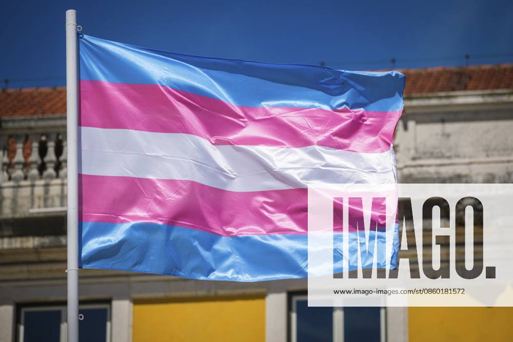 Pastellfarbene Transflaggen wehen auf einer Transgender Pride Flagge am Himmel von Lissabon, Portugal, für LGBT Gleichheit, fotografiert unter tiefblauem Himmel Pastel trans flag colors wave on a transgender pride flag in the Lisbon, Portugal sky for LGBT equality, photographed under deep blue sky