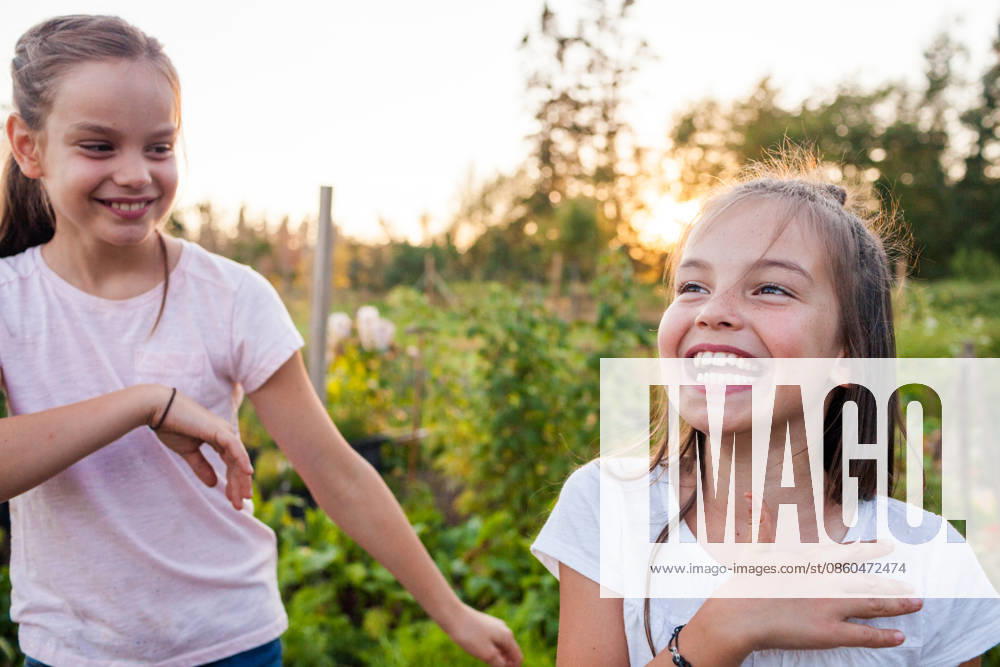 Two young sisters laughing together outdoors at sunset Langley, British Columbia, Canada CR_JDIP260630-2071821-01 ,model released, Symbolfoto