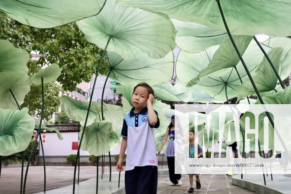 Children walk under giant lotus leaf art installations during a lotus market at the Confucius Temple on July 4, 2026 in Hangzhou, Zhejiang Province of China.