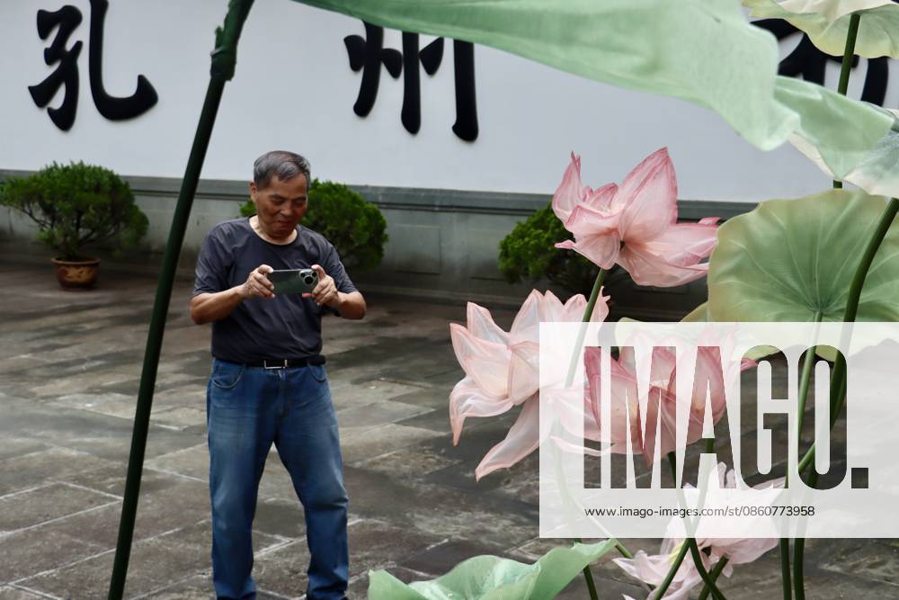 A visitor takes photos of lotus art installations during a lotus market at the Confucius Temple on July 4, 2026 in Hangzhou, Zhejiang Province of China.
