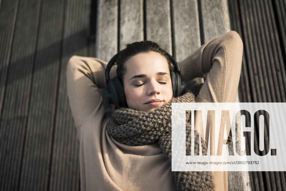 Portrait of woman listening music with cordless headphones relaxing on bench in autumn model released, Symbolfoto, MOEF01867