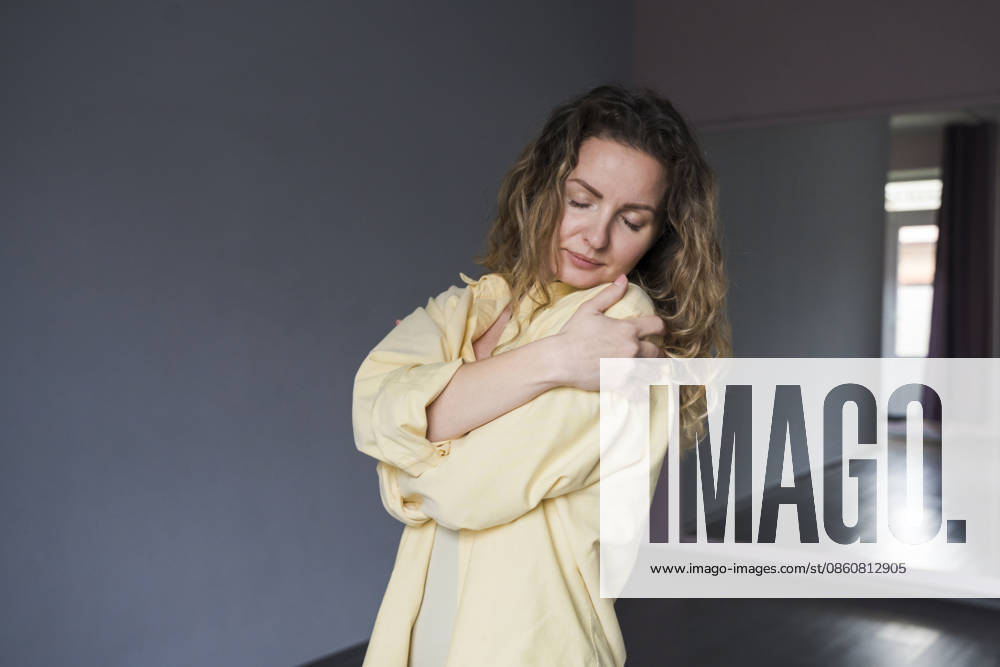 Yogini in yellow shirt hugging body indoors for self care model released, Symbolfoto, OSF02770