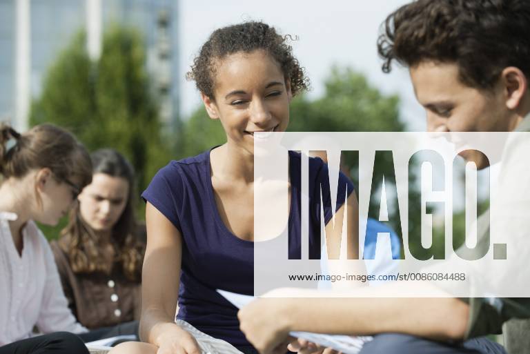 University students studying together outdoors, focus on one woman