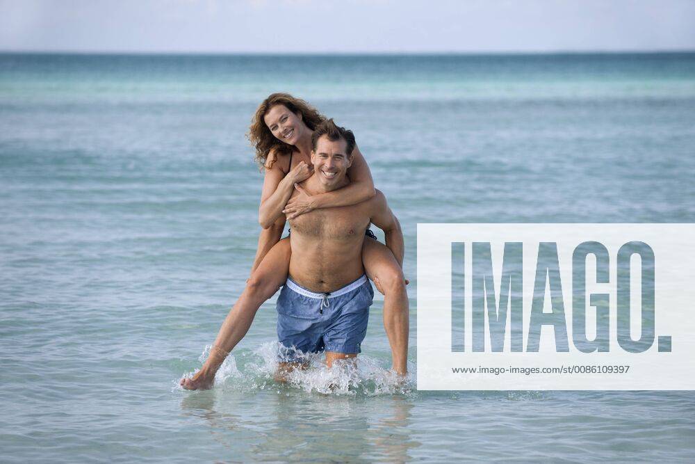Man giving woman piggyback at beach, portrait