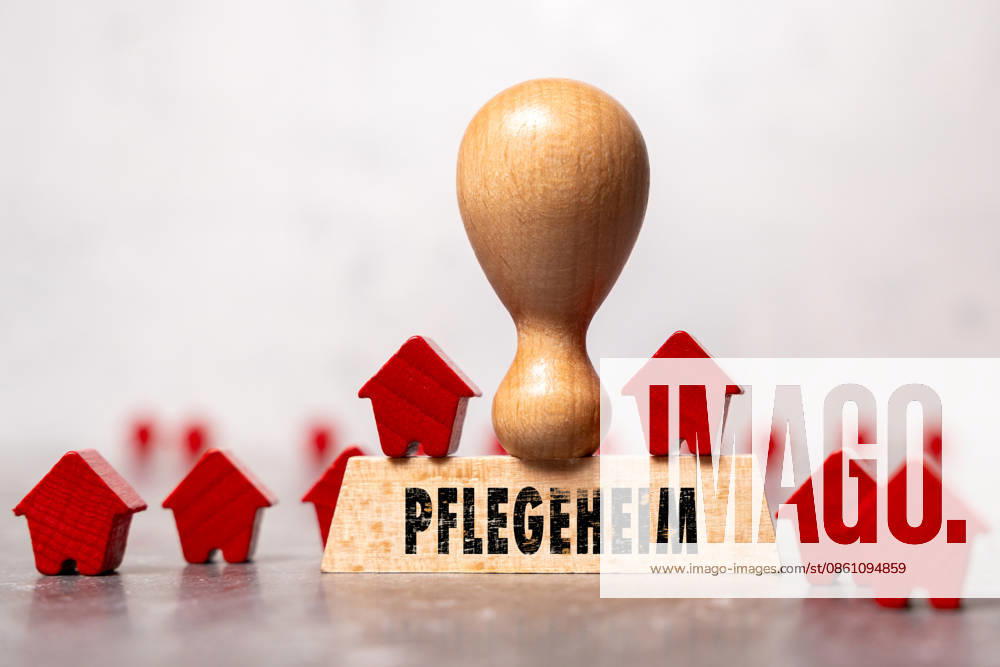 PHOTOMONTAGE. A wooden stamp bearing the inscription Nursing Home among small wooden houses symbolizes inpatient care and senior housing. The image represents nursing home beds, care services, demographic change, and long-term care policy.