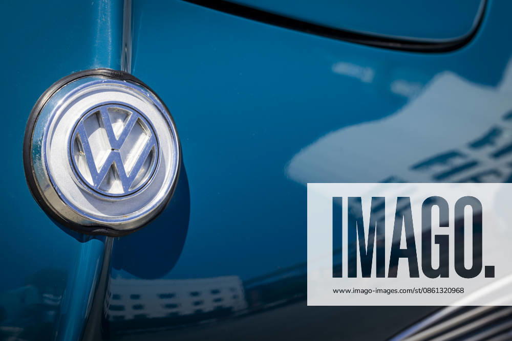 Close-up of the VW logo on the hood of a Karmann Ghia Coupé. The VW Osnabrück plant is reflected in the blue paint. 11 07 2026. Symbolic image of VW Osnabrück