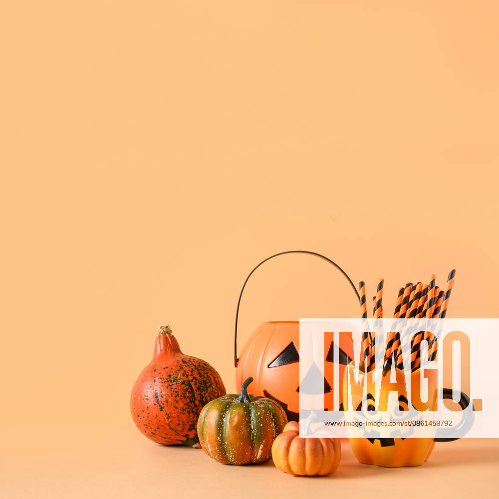 Lustige Halloween-Partydekoration, Kürbisse, Becher mit Trinkhalm. Halloween festive party decorations, candy bowl, pumpkins, funny mug with drinking straw on orange background. Square composition with copy space. (License=RF)