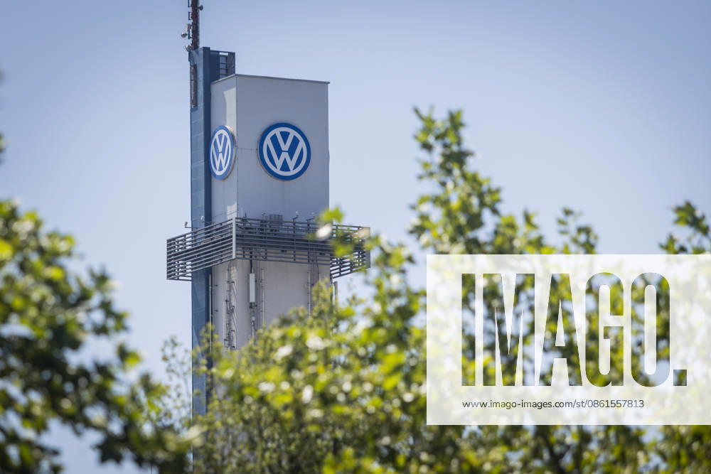 Tower at the VW plant in Osnabrück with the VW logo against a blue sky, framed by the foliage of green trees; stock photo: Volkswagen Osnabrück, July 11, 2026; stock photo: VW Osnabrück