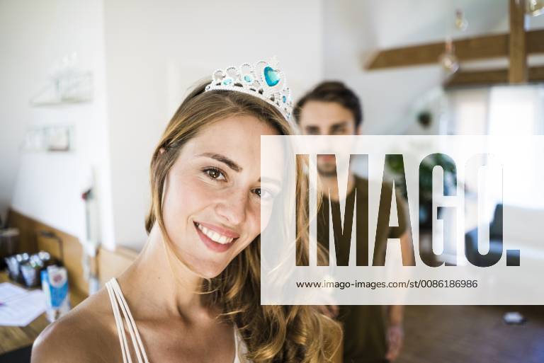 Portrait of smiling woman wearing tiara at home with man in background model released Symbolfoto property released JOSF02628