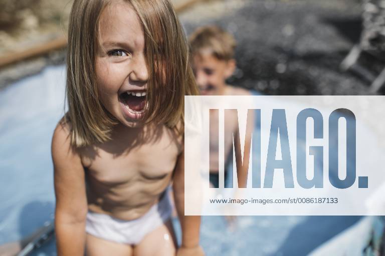 Portrait of screaming little girl having fun in pool with her brother model released Symbolfoto KMKF00444