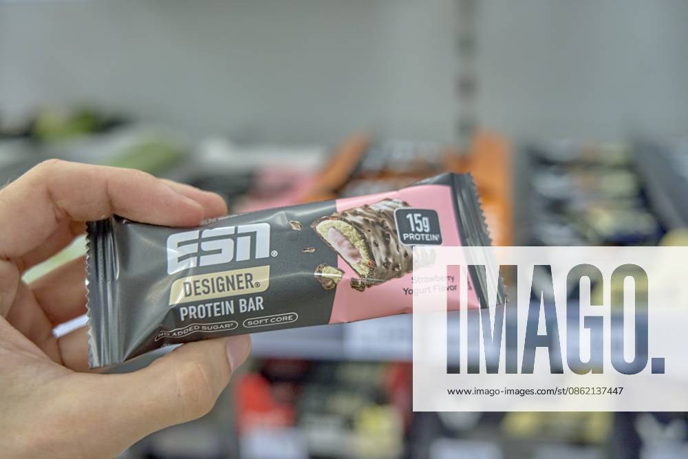Hand hält einen Proteinriegel mit Erdbeer-Joghurt-Geschmack, elite sport nutrition ESN Elite Sports Nutrition, Produkt einkaufen, Drogerie Markt Laden, Rossmann, Deutschland Hand holding a protein bar with strawberry yogurt flavor, elite sport nutrition ESN Elite Sports Nutrition, product shopping, Drogerie Markt Laden, Rossmann, Germany