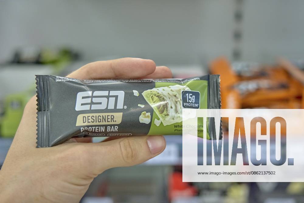 ESN Elite Sports Nutrition Designer Protein Bar mit Geschmacksrichtung Weiße Schokolade Pistazie in der Hand im Supermarkt, Produkt einkaufen, Drogerie Markt Laden, Rossmann, Deutschland ESN Elite Sports Nutrition Designer Protein Bar with Flavor White Chocolate Pistachio in Hand at Supermarket, Product Shopping, Drugstore Markt Laden, Rossmann, Germany