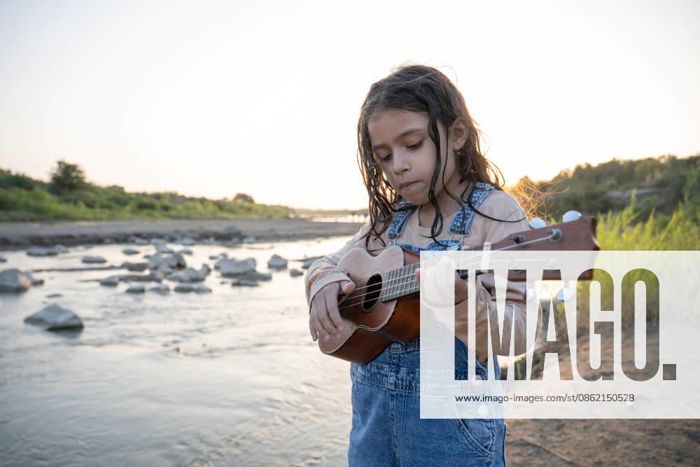 Young girl playing ukulele by a river at sunset Reque, Lambayeque, Peru CR_BILL260717-2080718-01 ,model released, Symbolfoto ,property released