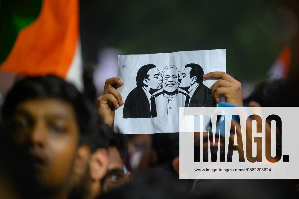 A protester holds up a placard depicting billionaires Mukesh Ambani and Gautam Adani kissing the cheeks of Prime Minister Narendra Modi, symbolizing protesters allegations of a corruption nexus between the two industrialists and the Modi government, at Jantar Mantar during demonstrations by the Cockroach Janata Party (CJP) demanding the resignation of Education Minister Dharmendra Pradhan over alleged irregularities in the NEET-UG exam, July 20, 2026. New Delhi India - ZUMAm184 20260720_zip_m184_010