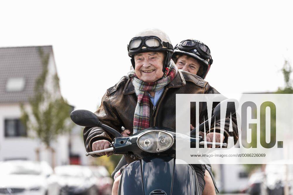 Happy senior couple riding motor scooter model released Symbolfoto UUF14922