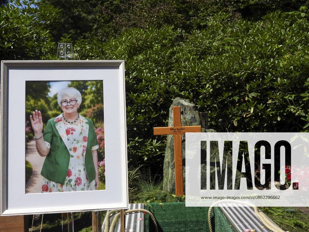 CNTV OHLSDORF Flowers and funeral wreaths lie in front of a wooden cross and a portrait of the deceased at the gravesite. The grave of Ilka Seeler, wife of the late soccer player Uwe Seeler, was laid to rest today next to her husband. July 21, 2026, Hamburg-Ohlsdorf, Hamburg Germany