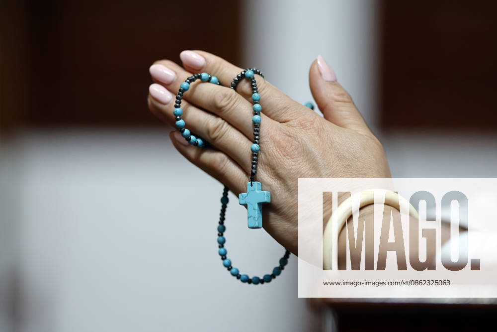 A hand holding a blue rosary with a cross, a symbol of Christian faith and devotion. Prayer and meditation are at the heart of this spiritual practice. Xuan Hung Nam Dinh Vietnam model released
