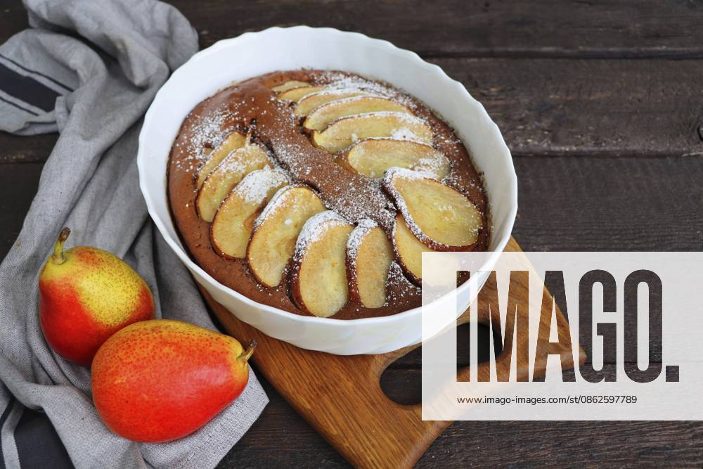 Schokoladen Brownie mit einer Birne in einer Auflaufform. Im Stil des Essenssammelns. Herbstlicher Hintergrund. Zutaten für seine Zubereitung Chocolate Brownie with a pear in a baking dish. Food gathering style. Autumn background. Ingredients for its preparation