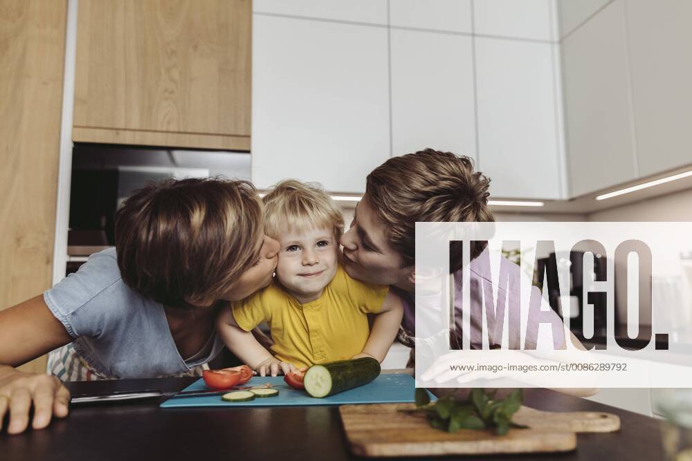 Happy lesbian couple kissing their child in kitchen model released Symbolfoto property released MFF04427