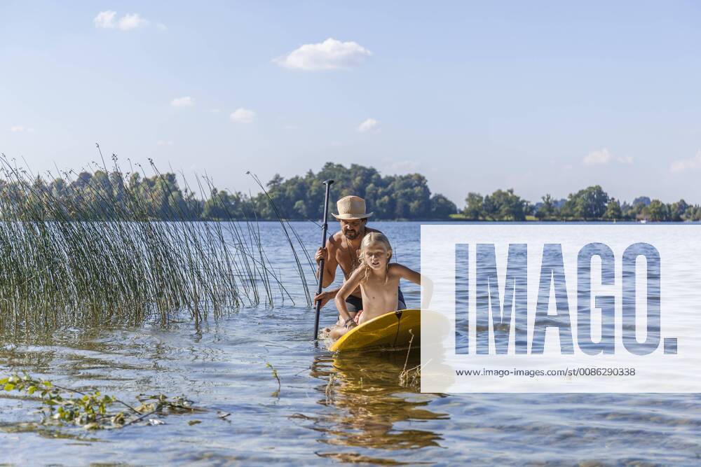 Father and daughter paddle boarding on lake model released Symbolfoto TCF05674