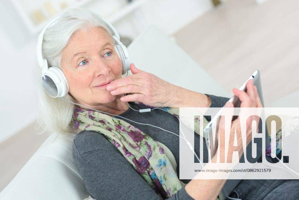 Senior lady listening to music through headphones model released Symbolfoto
