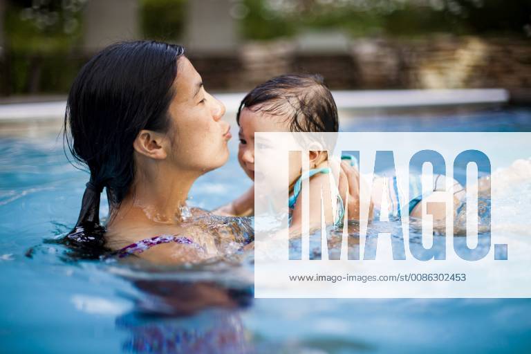 A Japanese American mother swims and holds her 10 month old baby girl in a swimming pool., Breckenridge Colorado USA model released Symbolfoto
