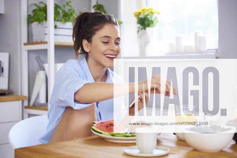Young woman at home in kitchen, eating breakfast model released Symbolfoto property released ABIF00910