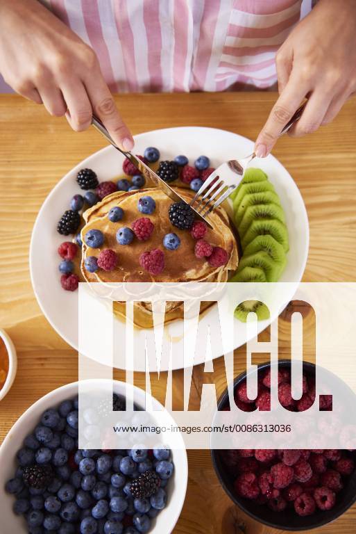 Woman eating pancakes with berries for breakfast model released Symbolfoto property released ABIF00932