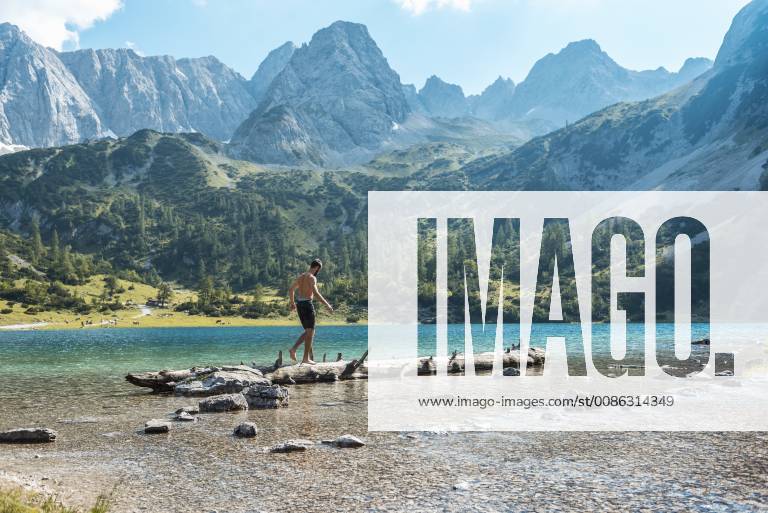 Austria, Tyrol, Young man at Lake Seebensee balancing on tree trunk model released Symbolfoto DIGF04746