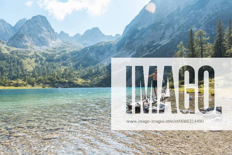 Austria, Tyrol, Young man at Lake Seebensee balancing on tree trunk model released Symbolfoto DIGF04748
