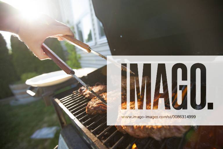 Person preparing meat on barbecue grill, Surrey British Columbia Canada model released Symbolfoto property released