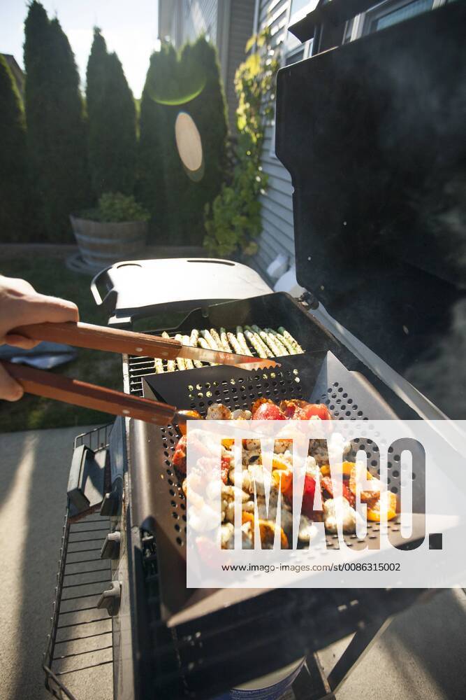 Person cooking vegetables on barbecue grill, Surrey British Columbia Canada model released Symbolfoto property released
