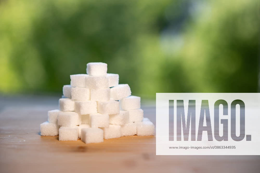 Stack of sugar cubes on a kitchen board. Stack of sugar cubes on a kitchen board. Blurred trees in the background. Swet food, white or industrial sugar. food_sugar_B97A0064