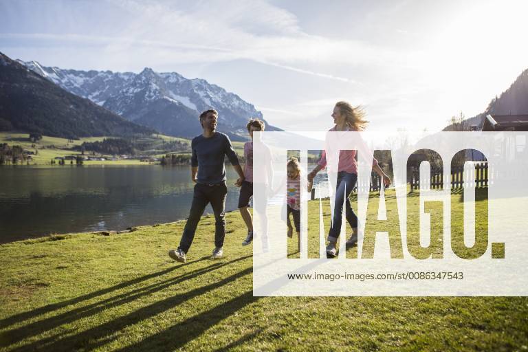 Austria, Tyrol, Walchsee, happy family walking at the lakeside model released Symbolfoto JLOF00200