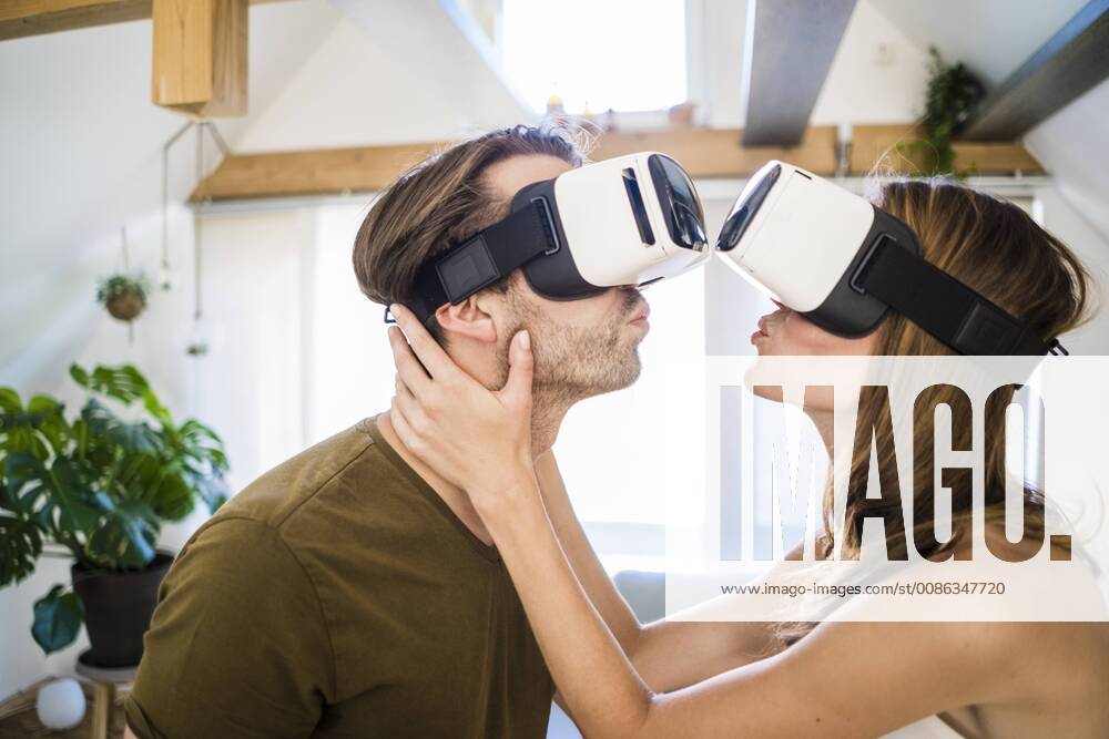Couple wearing VR glasses kissing at home model released Symbolfoto property released JOSF02635