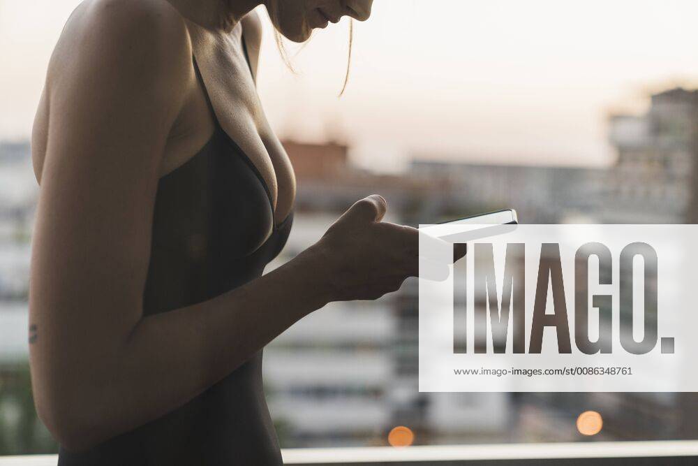 Close-up of young woman wearing black dress using cell phone on balcony model released Symbolfoto KKAF01452