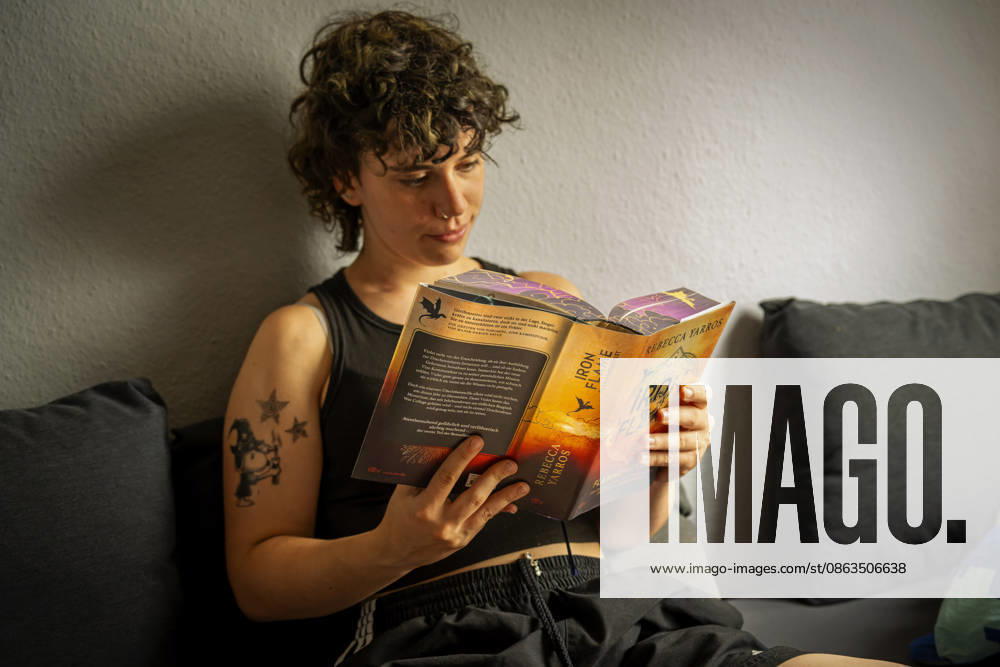 Book series by Rebecca Yarros, IRON FLAME, a teenager in Bad Wörishofen, Bavaria, is sitting on her sofa reading her exciting book. Model release 07 08 2026, Young adult books 07 08 2026, Young adult books