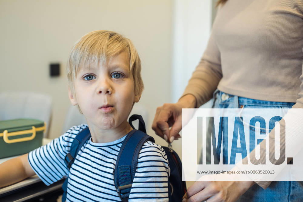 Eine Frau packt eine Brotdose in den Rucksack ihres siebenjährigen Sohnes. A woman puts a lunchbox into her seven-year-old son s backpack. Hands close up. (License=RF) ,model released, Symbolfoto