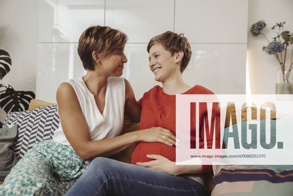 Happy lesbian couple touching belly of the expectant mother model released Symbolfoto property released MFF04440