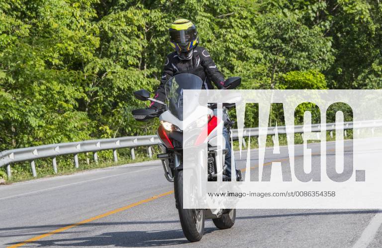 Biker riding along countryside highway surrounded by green trees, Chiang Rai, Mueang Chiang Rai District, Thailand, Chiang Rai Mueang Chiang Rai District Thailand HETH001547 model released Symbolfoto
