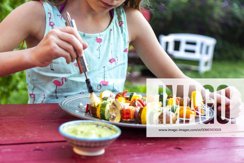 Young girl spreading vegetarian grill skewers with Argentinian chimichurri model released Symbolfoto SARF03933