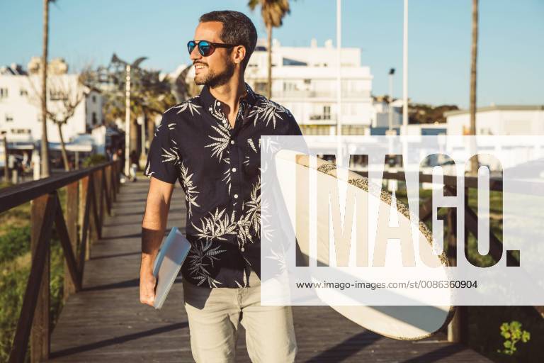 Man at the beach carrying surfboard and laptop model released Symbolfoto SUF00560
