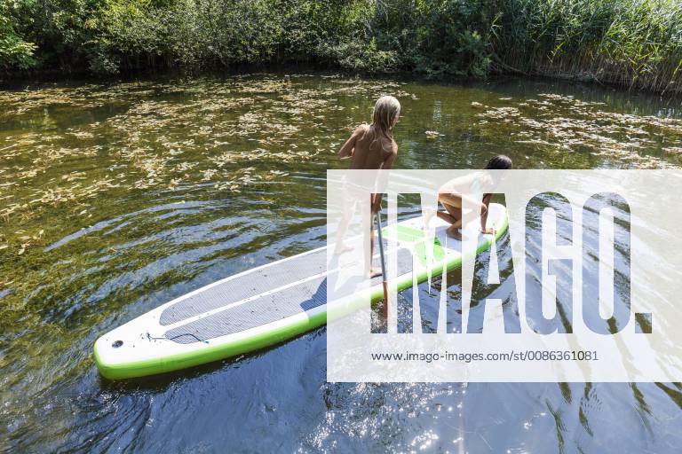 Two girls in a pond on SUP board model released Symbolfoto property released TCF05727