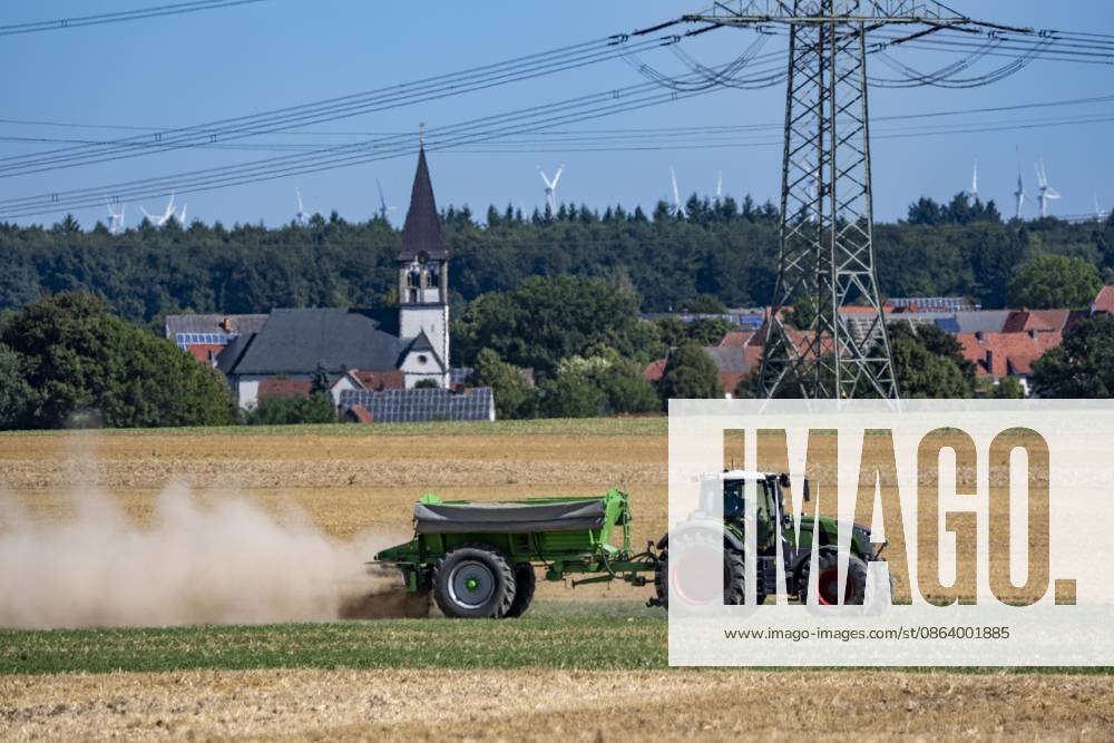 A tractor equipped with a mineral fertilizer spreader is working a harvested grain field, spreading mineral fertilizer and lime to improve soil quality for future use and planting, at Marsberg Meerhof, North Rhine-Westphalia, Germany—field work