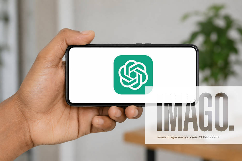In this photo illustration, a hand holds a smartphone horizontally displaying the ChatGPT AI logo, set against a softly blurred indoor background, in India on 15 August 2026. - ZUMAt232 20260815_zip_t232_005