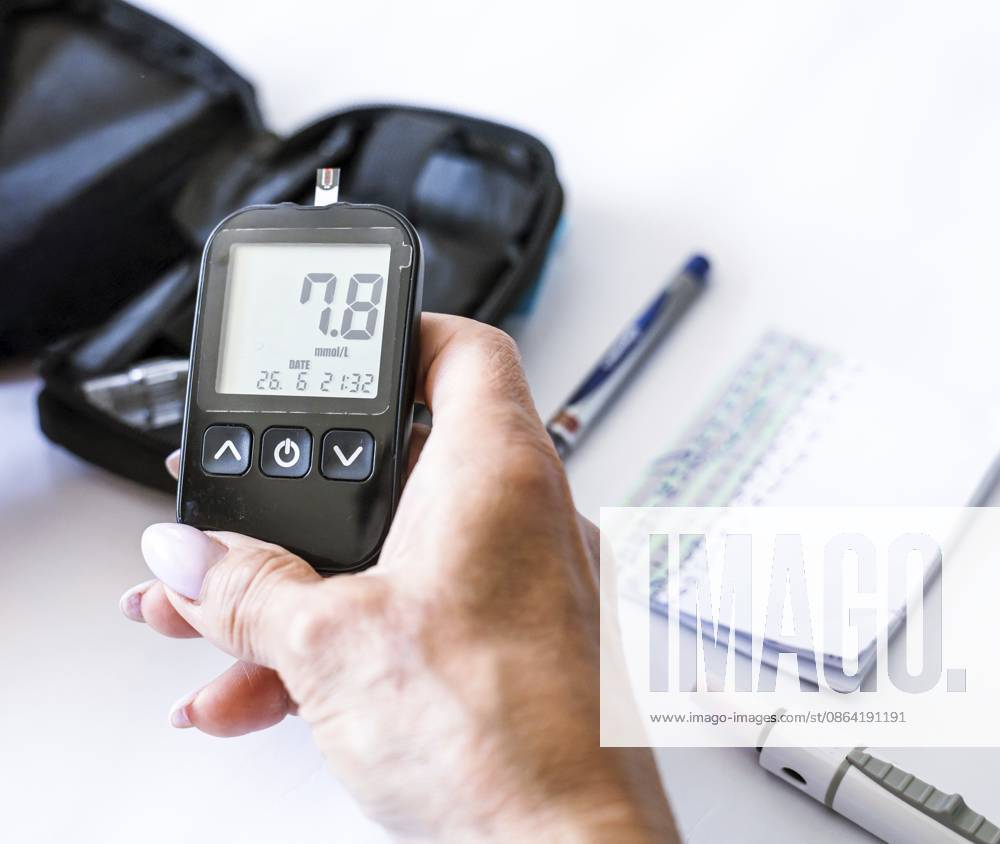 Nahaufnahme einer Frau mit einem Blutzuckermessgerät mit normalem Messwert nach dem Diabetes Test. Überwachung der häuslichen Gesundheit, Blutzuckerkontrolle, Endokrinologie, Behandlung chronischer Krankheiten und moderne Medizintechnik Close-up woman holding a blood glucose meter with normal reading after diabetes test. Home health monitoring, glycemic control, endocrinology, chronic disease management and modern medical techno