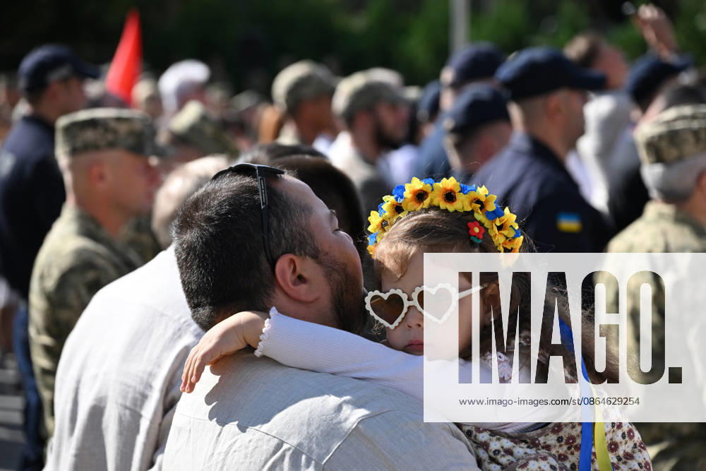 National Flag Day of Ukraine in Lviv LVIV, UKRAINE - AUGUST 23: A child wearing a floral wreath in the colors of the Ukrainian flag is carried by a man during a National Flag Day ceremony in Lviv, Ukraine, on August 23, 2026. Due to the ongoing Russian-Ukrainian War, celebrations were limited to a ceremonial raising of the Ukrainian flag on the city s highest flagpole with the participation of soldiers from various branches of the armed forces. Participants also observed a minute of silence for those killed, sang the Ukrainian national anthem, and listened to patriotic and folk songs performed by a military orchestra. Michael Sorrow Anadolu Lviv Ukraine. Editorial use only. Please get in touch for any other usage.