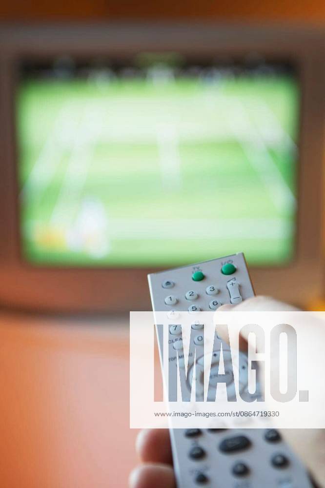 Closeup of female hand using remote control in front of TV model released Symbolfoto