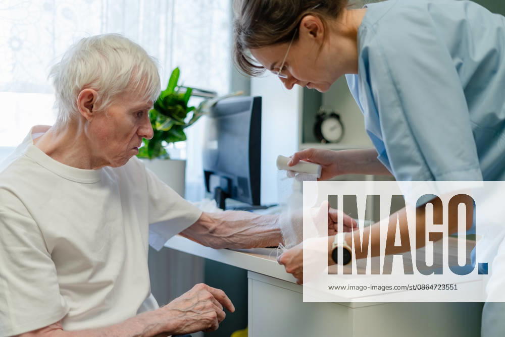 Krankenschwester behandelt einen älteren Mann in einer Hautpflegeklinik Nurse treating elderly man hand in skin care clinic. Healthcare worker providing geriatric dermatology and aging skin treatment for senior patient during thorough medical examination in office (License=RF) ,model released, Symbolfoto