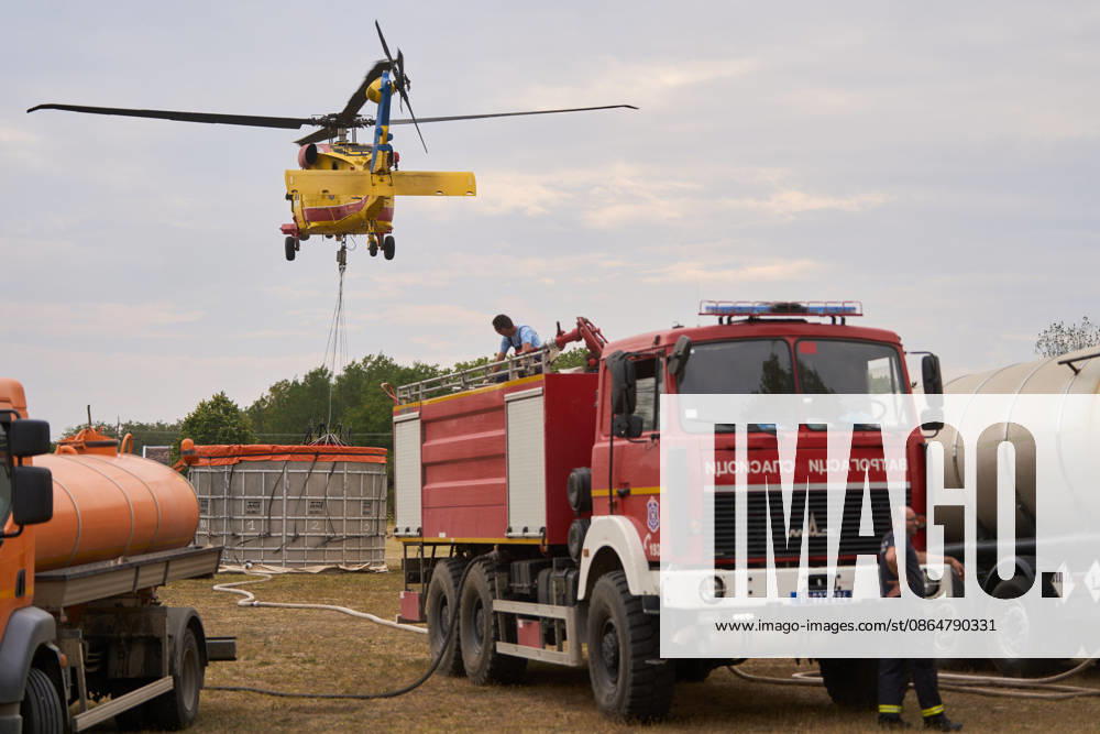 2026825, Susara, Serbia - Two Sikorsky UH-60 Black Hawk helicopters are deployed to the village of Susara to help battle the severe wildfires devastating the Deliblato Sands (Deliblatska Pescara) Special Nature Reserve, refilling their buckets from a large portable water tank placed on a local football pitch. Susara Serbia - ZUMAd223 20260825_zip_d223_005